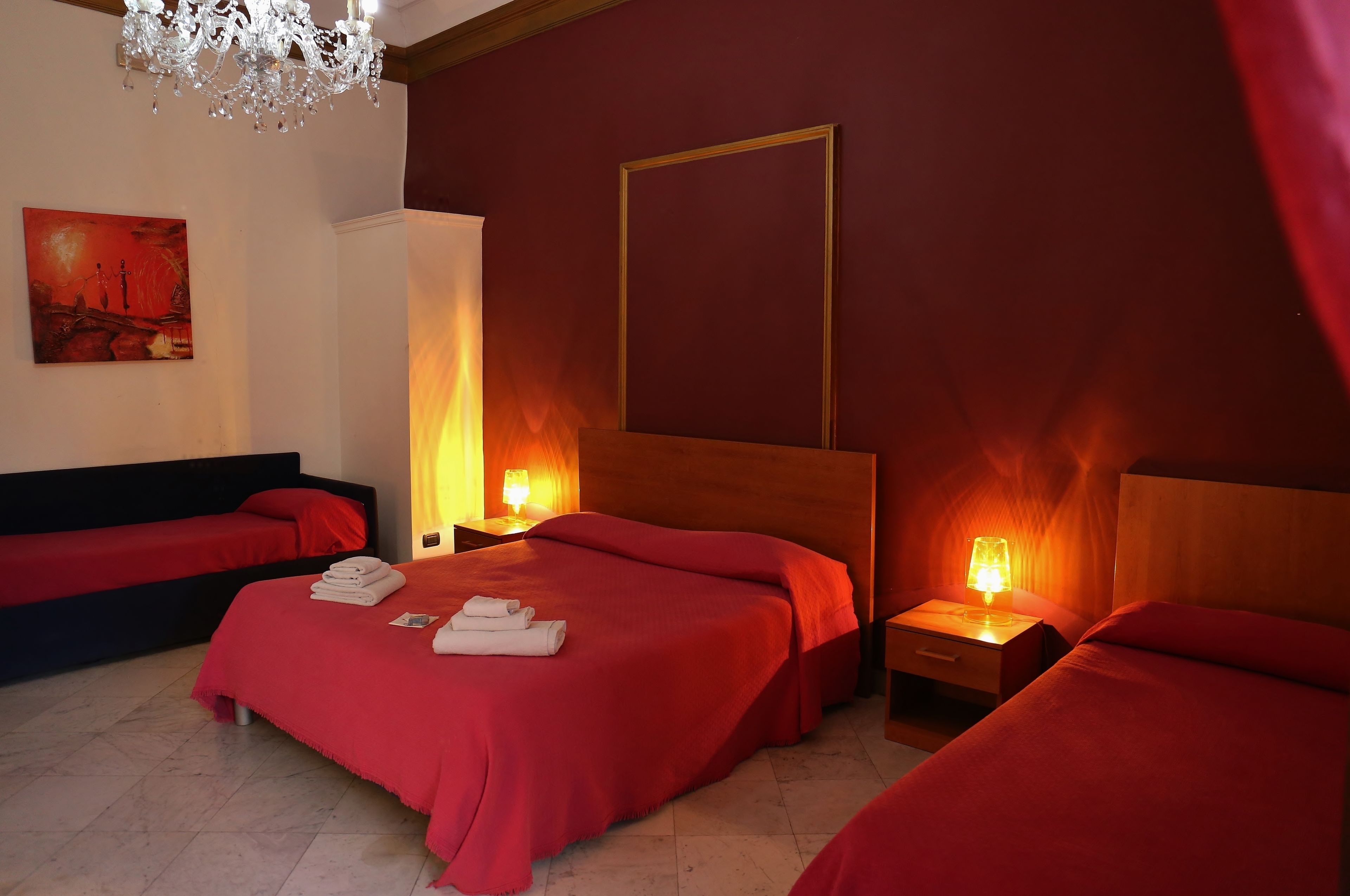 Une chambre d’hôtel avec deux lits, un lustre, un tableau au mur et une lampe de chevet.