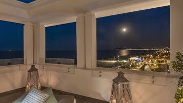 A balcony with a clear view of the city lights and the moon.