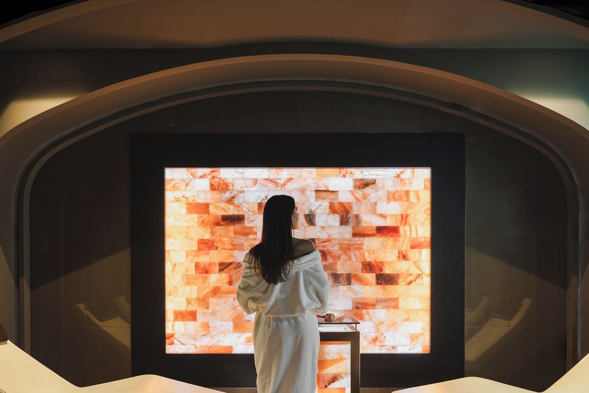 A person standing in front of a wall with a geometric pattern.