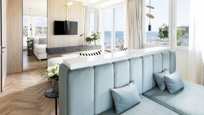 Un espacio moderno para relajarse con un sofá, un televisor en la pared y vistas al mar a través de amplios ventanales.