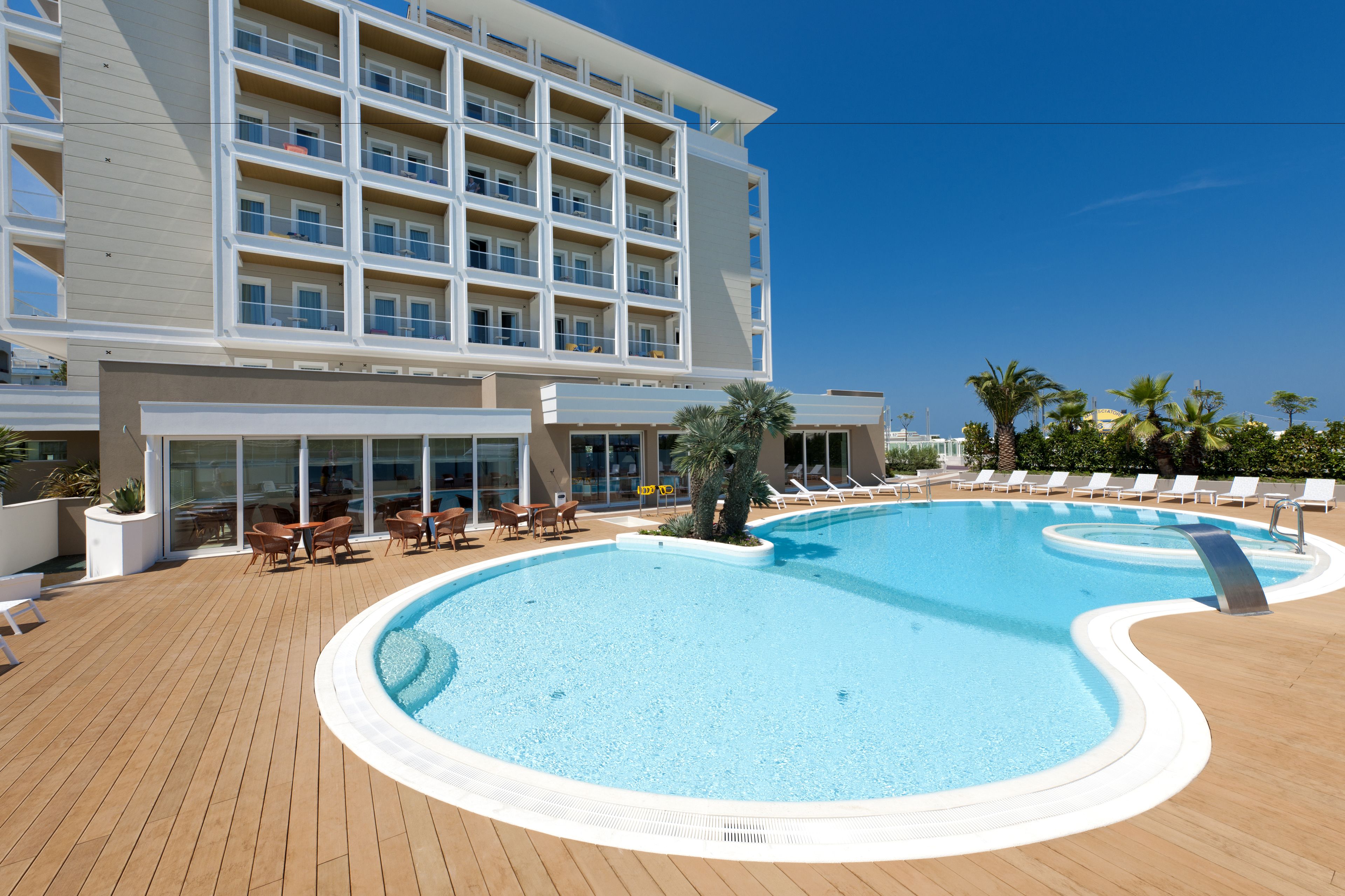 Ein Swimmingpool mit Liegestühlen und ein Gebäude mit mehreren Balkonen.