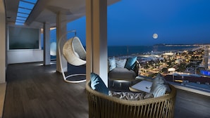 Un salón moderno con vista a la ciudad y al mar de noche.