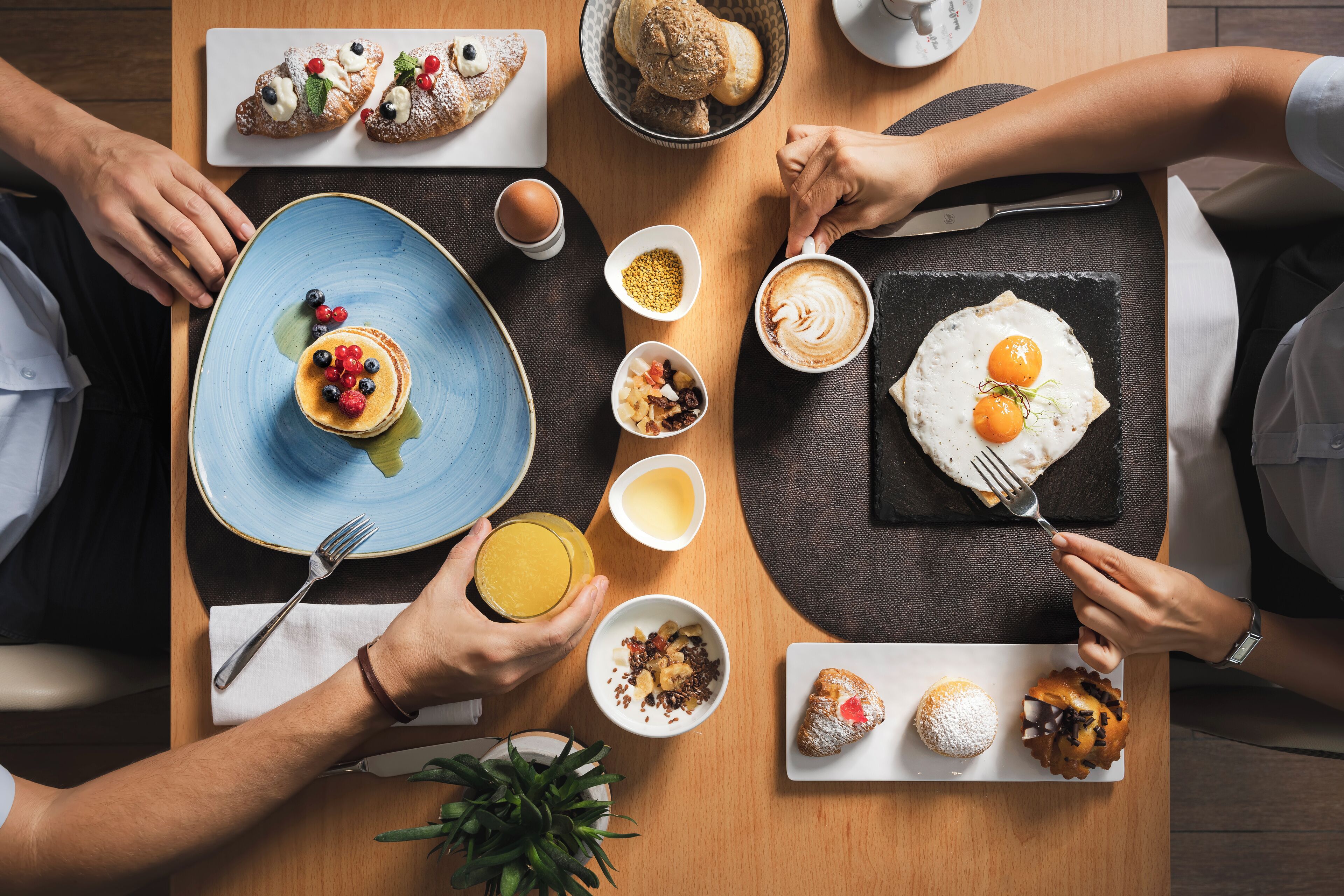 A dining table with various breakfast items including pancakes, eggs, and pastries.
