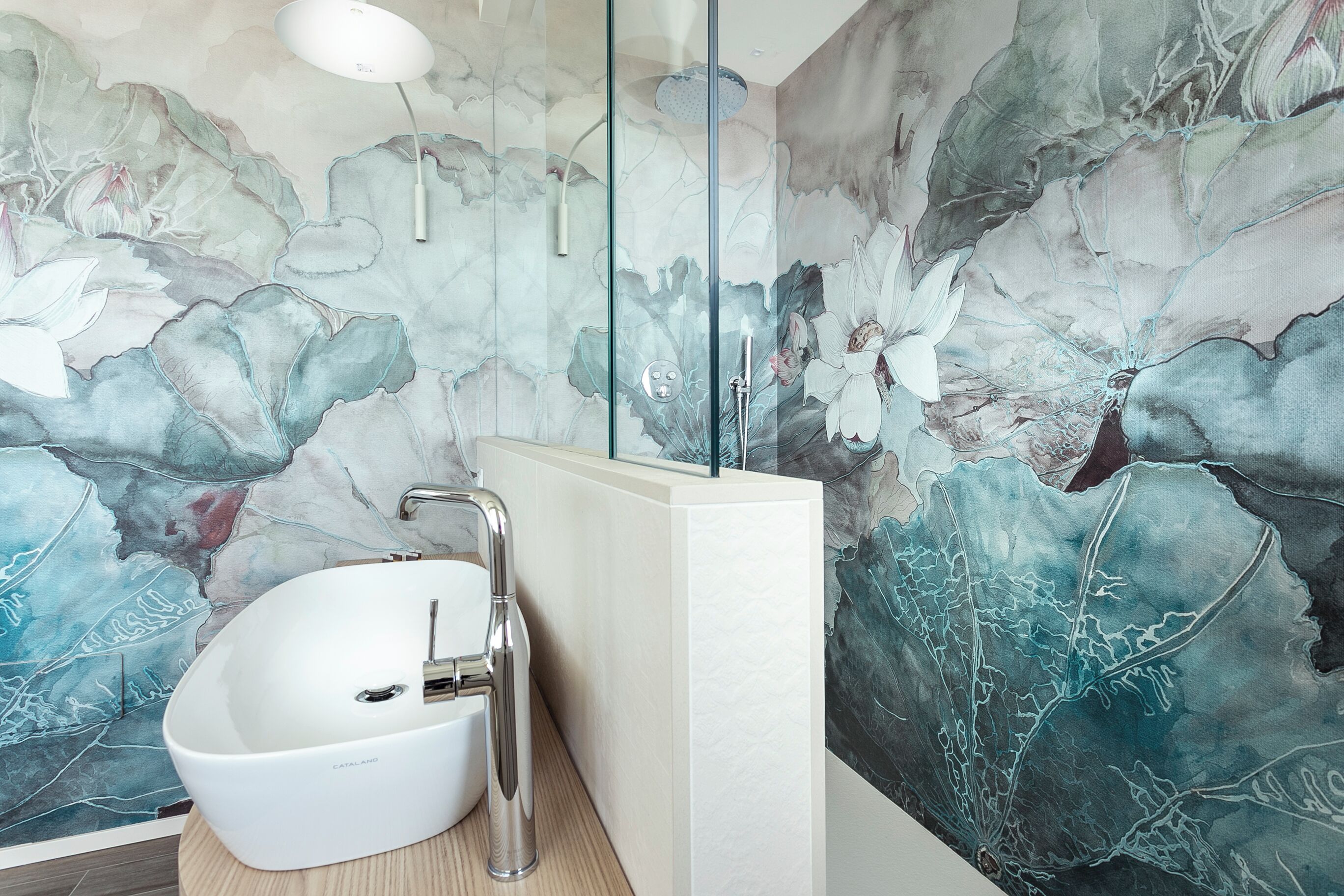 A bathroom with a white freestanding sink, a modern faucet, and a glass shower enclosure.