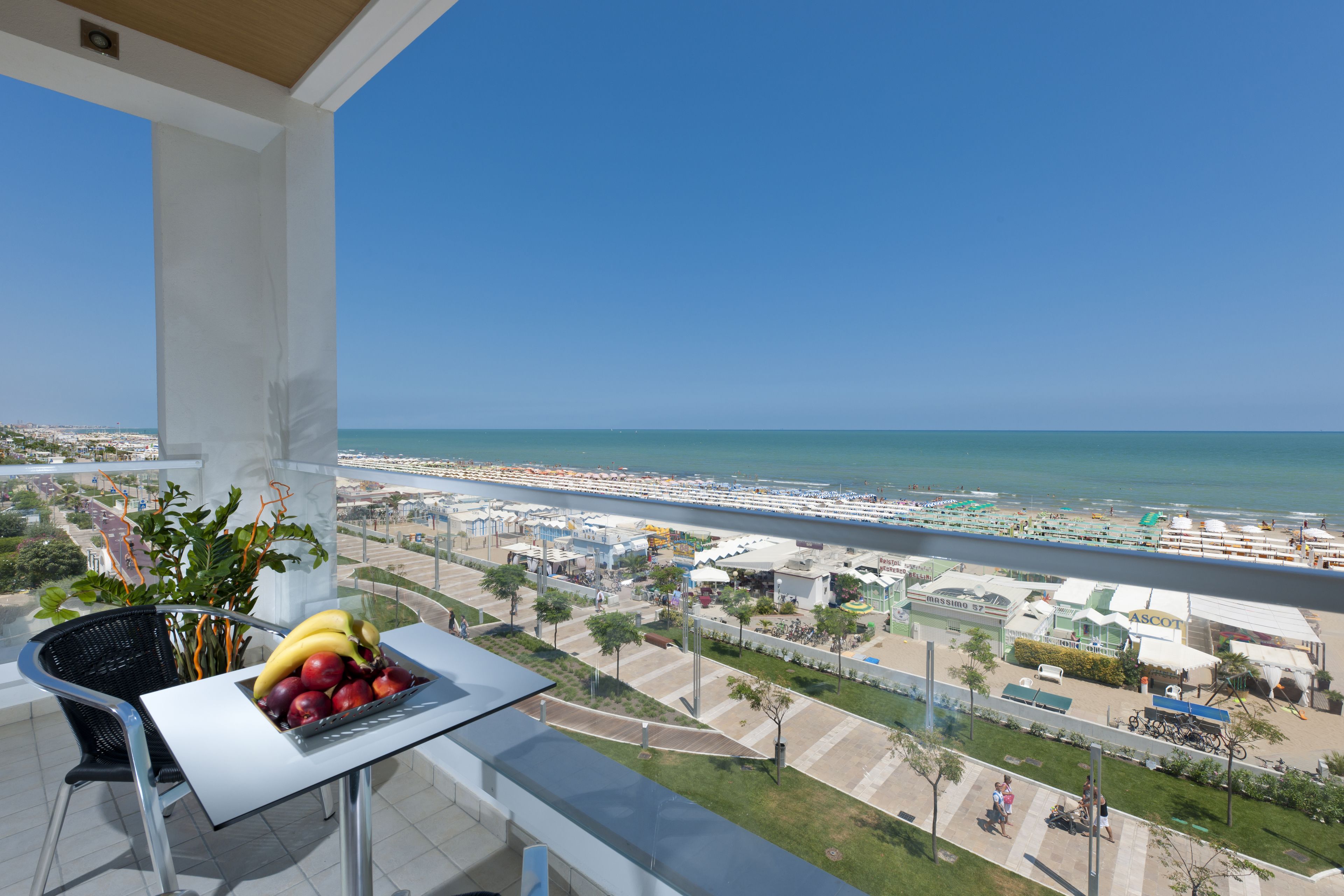 Ein Balkon mit Tisch und Obstschale, mit Blick auf Strand und Stadtlandschaft.
