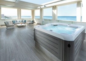 Un ambiente interno moderno con vasca idromassaggio, zona relax e ampie finestre vista oceano.