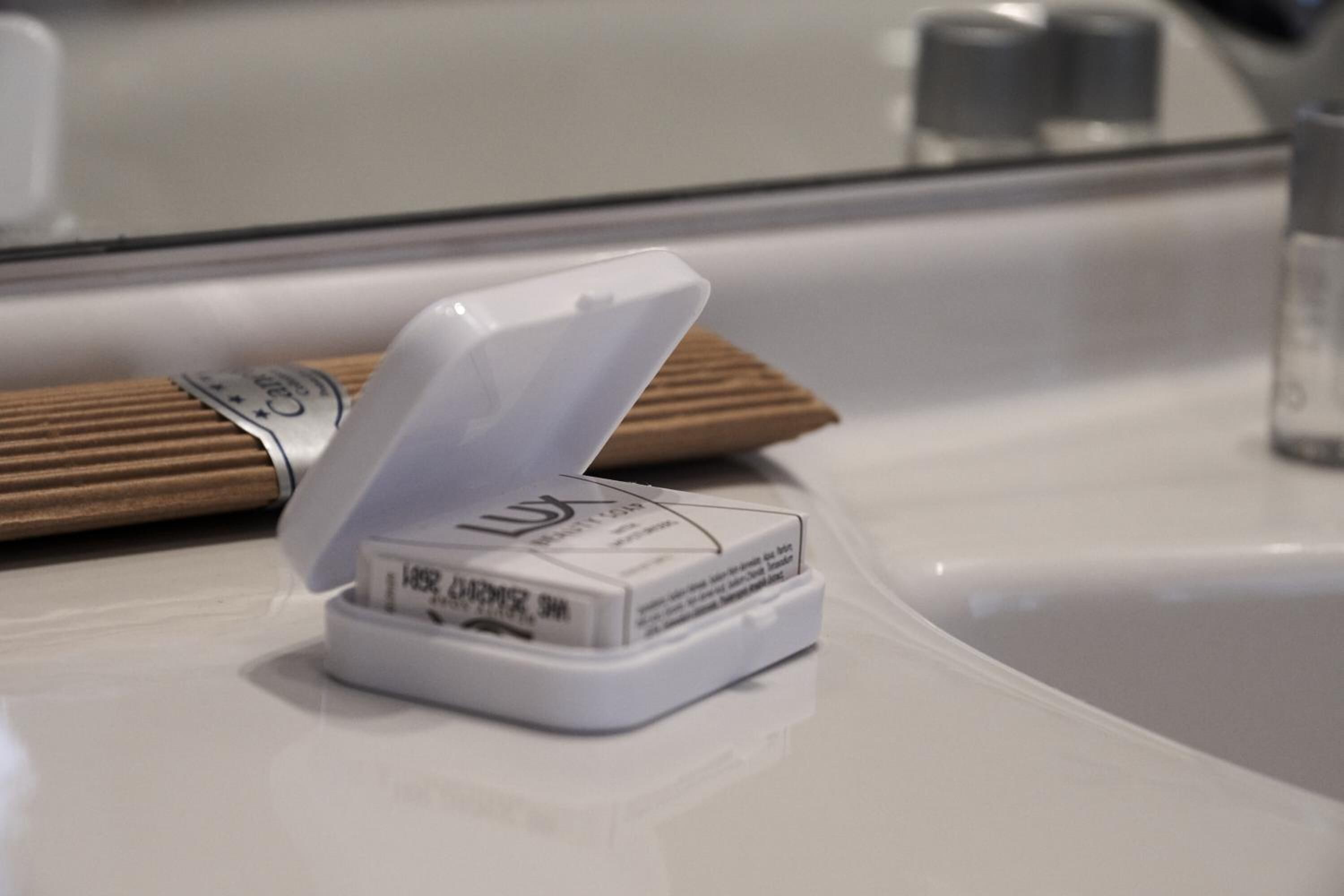 Un objeto blanco con tapa sobre una superficie blanca, posiblemente un recipiente o electrodoméstico.