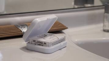 Un objeto blanco con tapa sobre una superficie blanca, posiblemente un recipiente o electrodoméstico.
