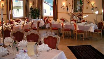 A dining area with tables set for a meal, chairs, and a large mirror on the wall.