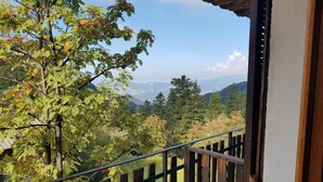 Un balcón con vistas a un paisaje montañoso, baranda de madera y un cartel que indica una dirección.
