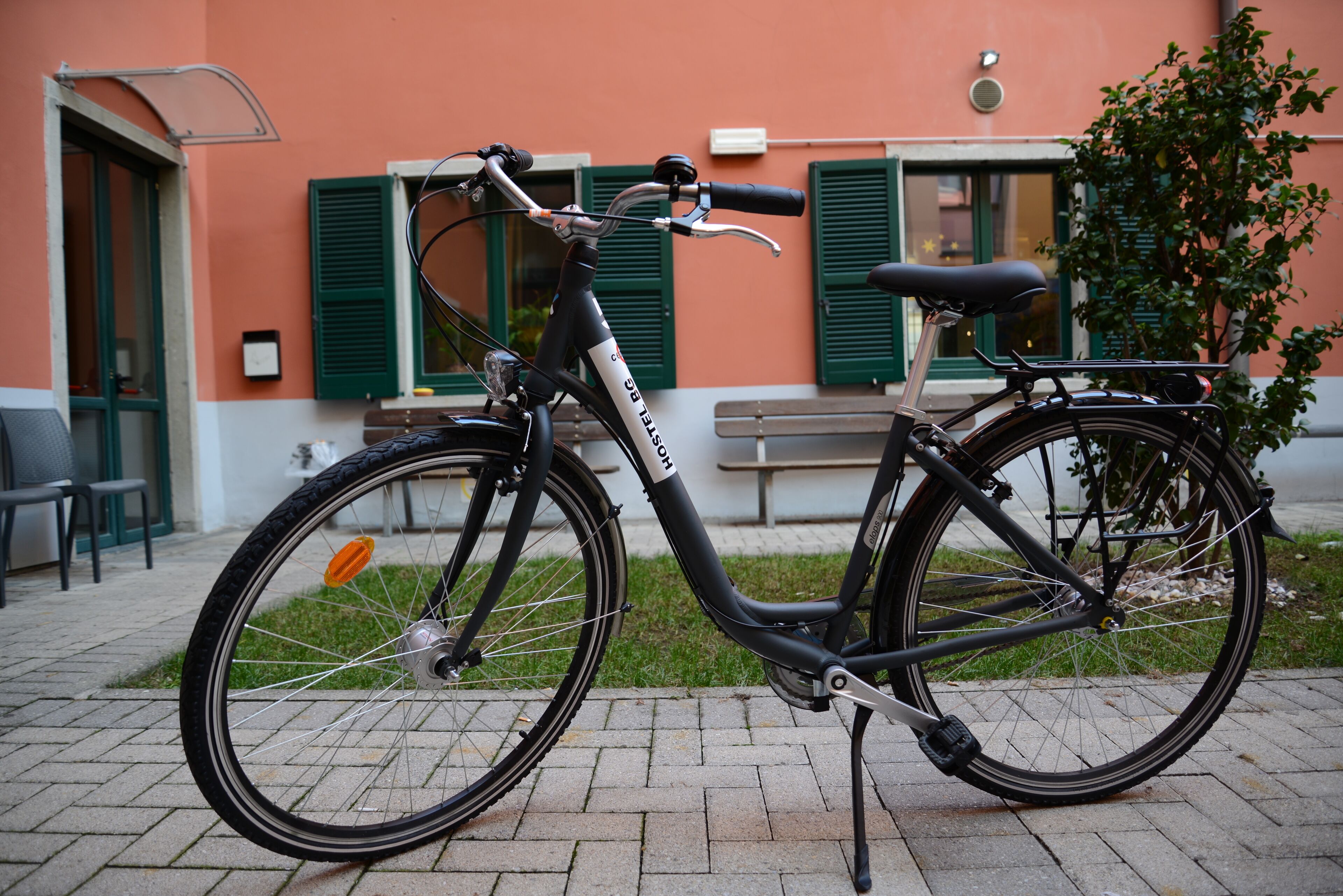 A stationary electric bicycle parked on a paved area with a building in the background.