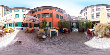 Un cortile con posti a sedere all'aperto, una botte e una zona riparata con ombrelloni.