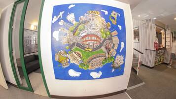 Un vestíbulo de hotel con un gran mural de un paisaje urbano, un sofá y una escalera.