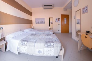 Una camera d'albergo con due letti, una scrivania, una sedia e uno specchio.