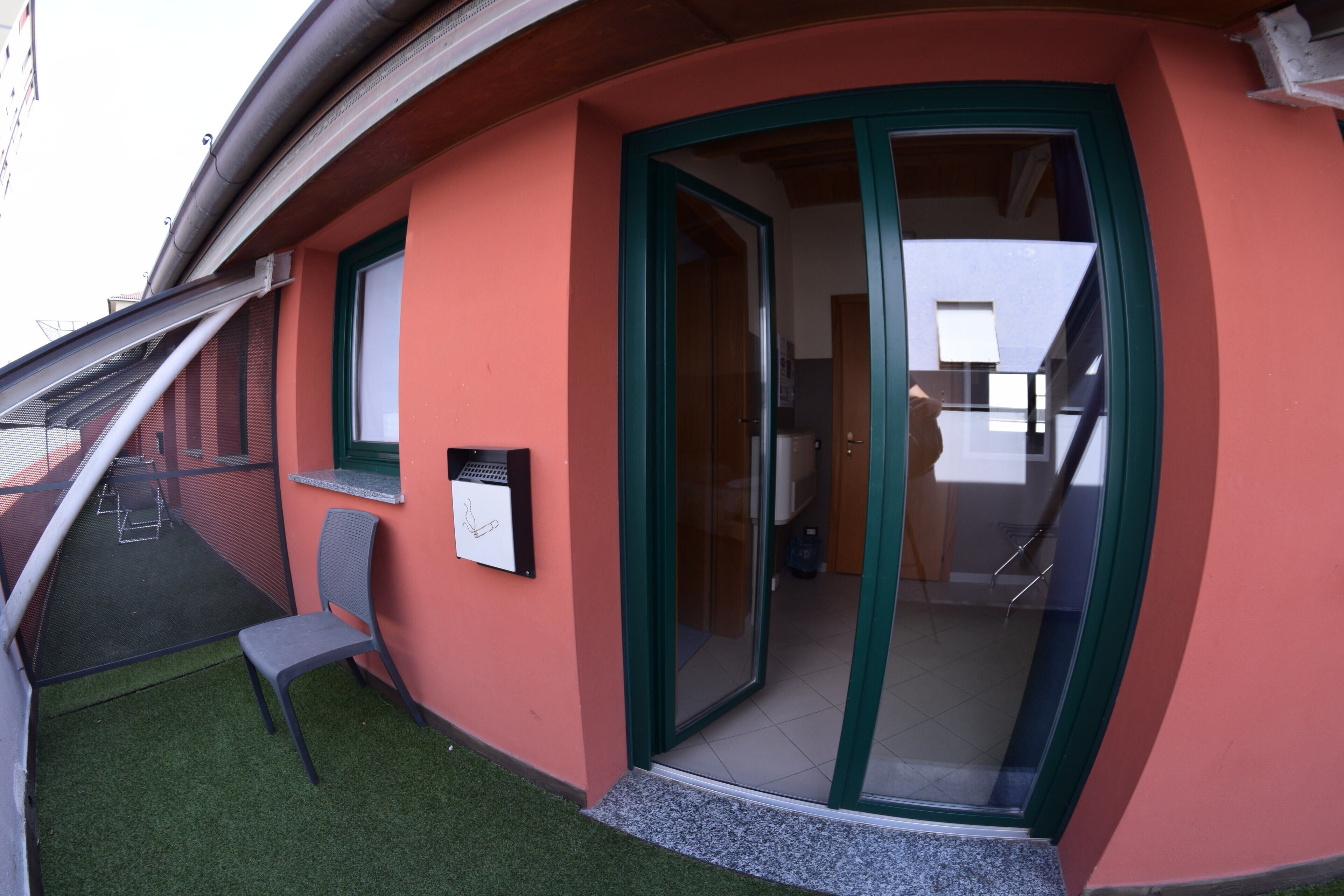 Un angolo di un edificio con una porta verde, una finestra e una sedia all'esterno.