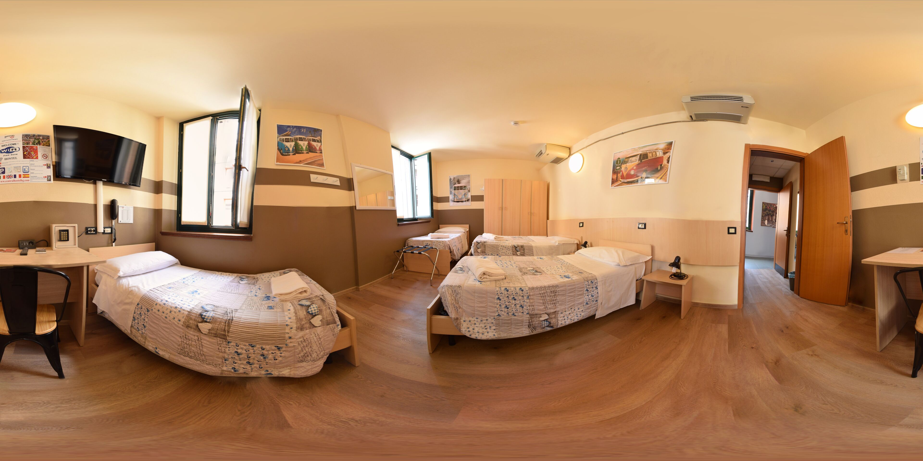 Una habitación con dos camas, un escritorio, una silla, un televisor y una ventana.