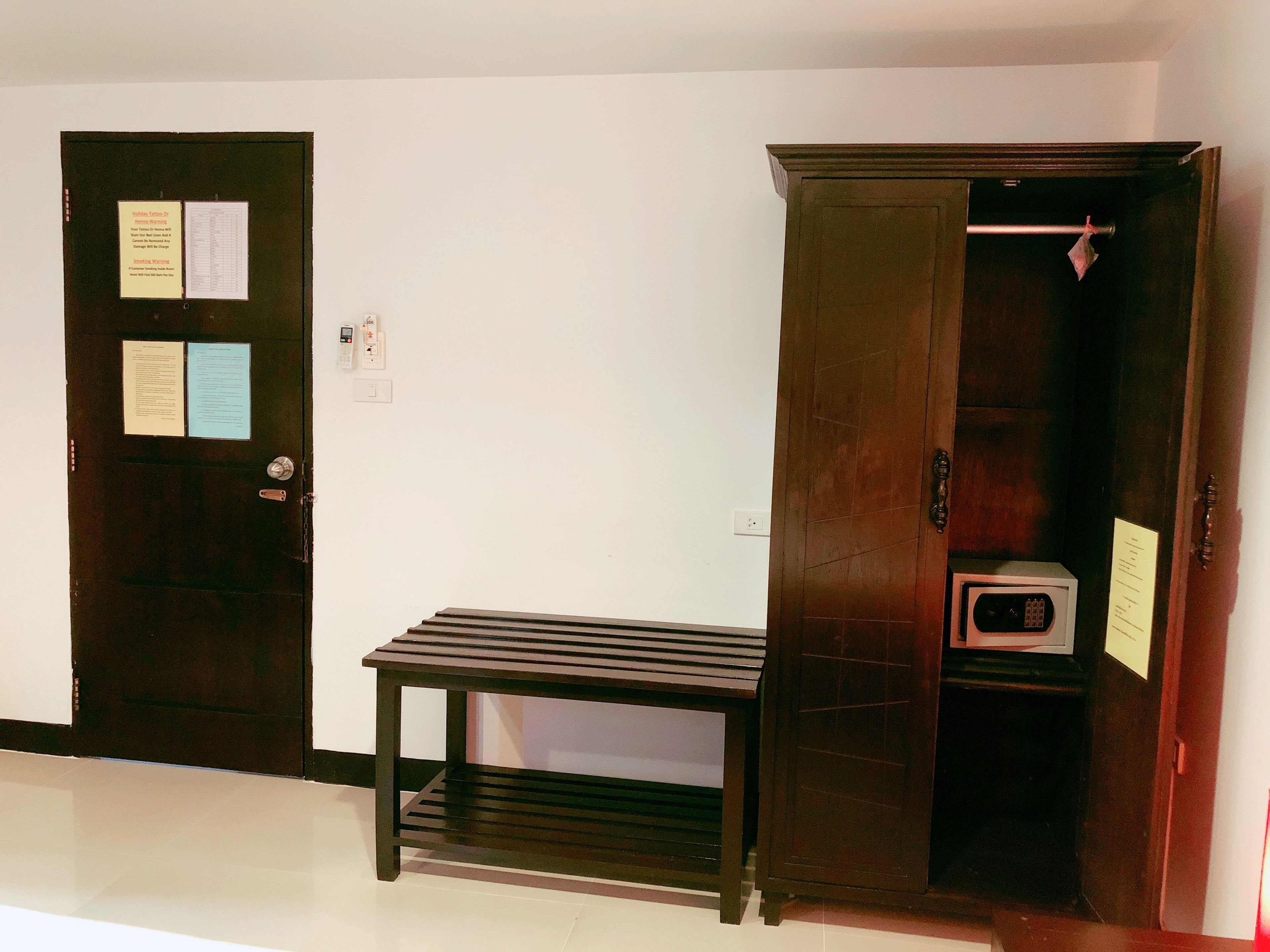 Ein Zimmer mit Holztür, einem kleinen Tisch und einem Kleiderschrank mit Kleiderstange.