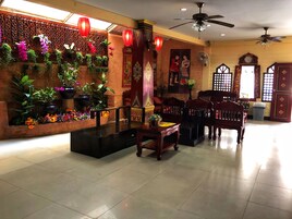 A traditional interior with a wooden altar, potted plants, and red lanterns.