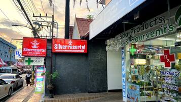 Una farmacia con un letrero rojo, un anuncio para Silverresortel y un cartel que ofrece productos de spa, recuerdos y cosméticos.