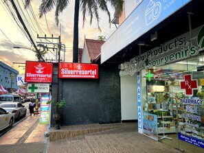 Una farmacia con un letrero rojo, un anuncio para Silverresortel y un cartel que ofrece productos de spa, recuerdos y cosméticos.