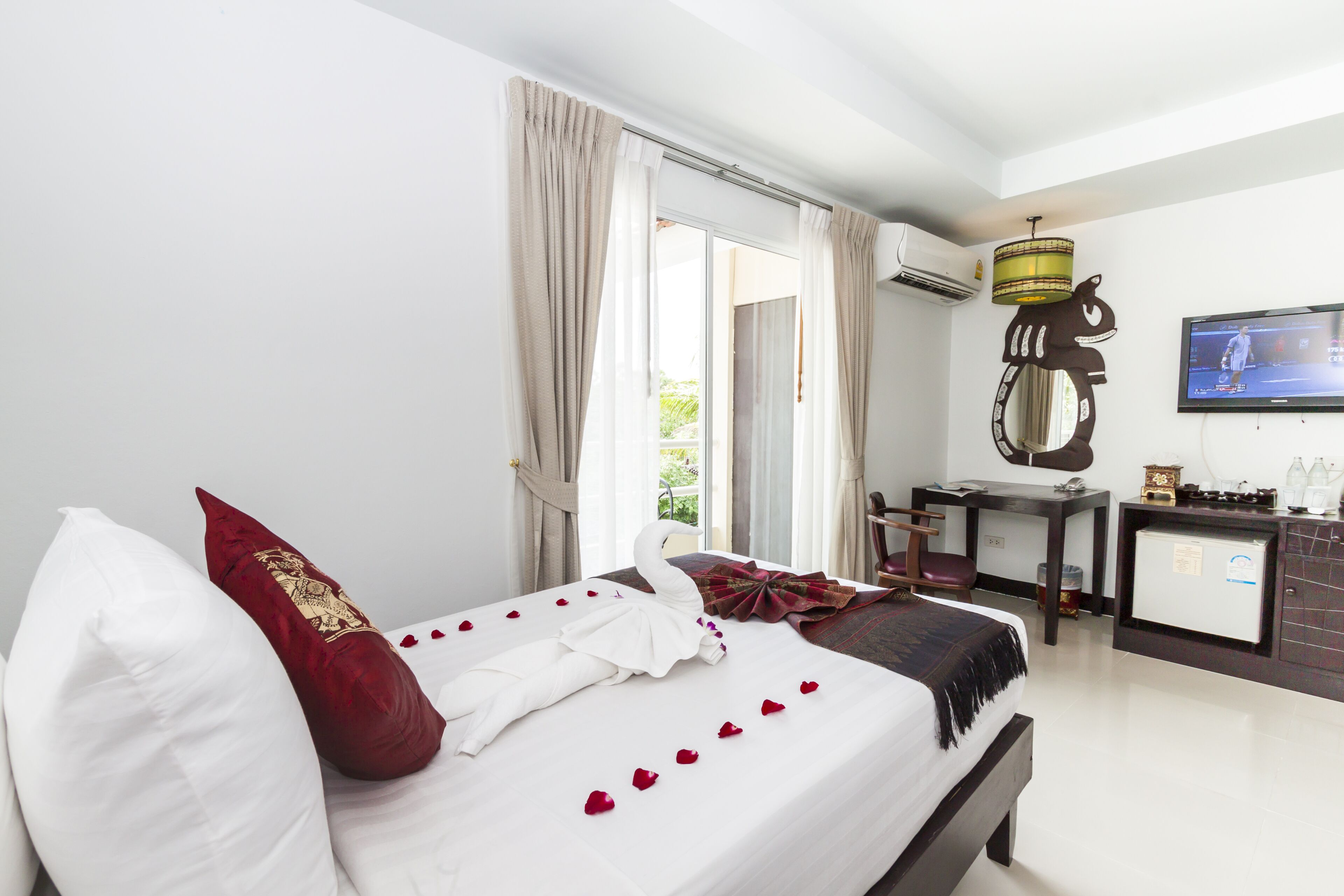 Una habitación de hotel con cama, escritorio, televisor y vistas al exterior.