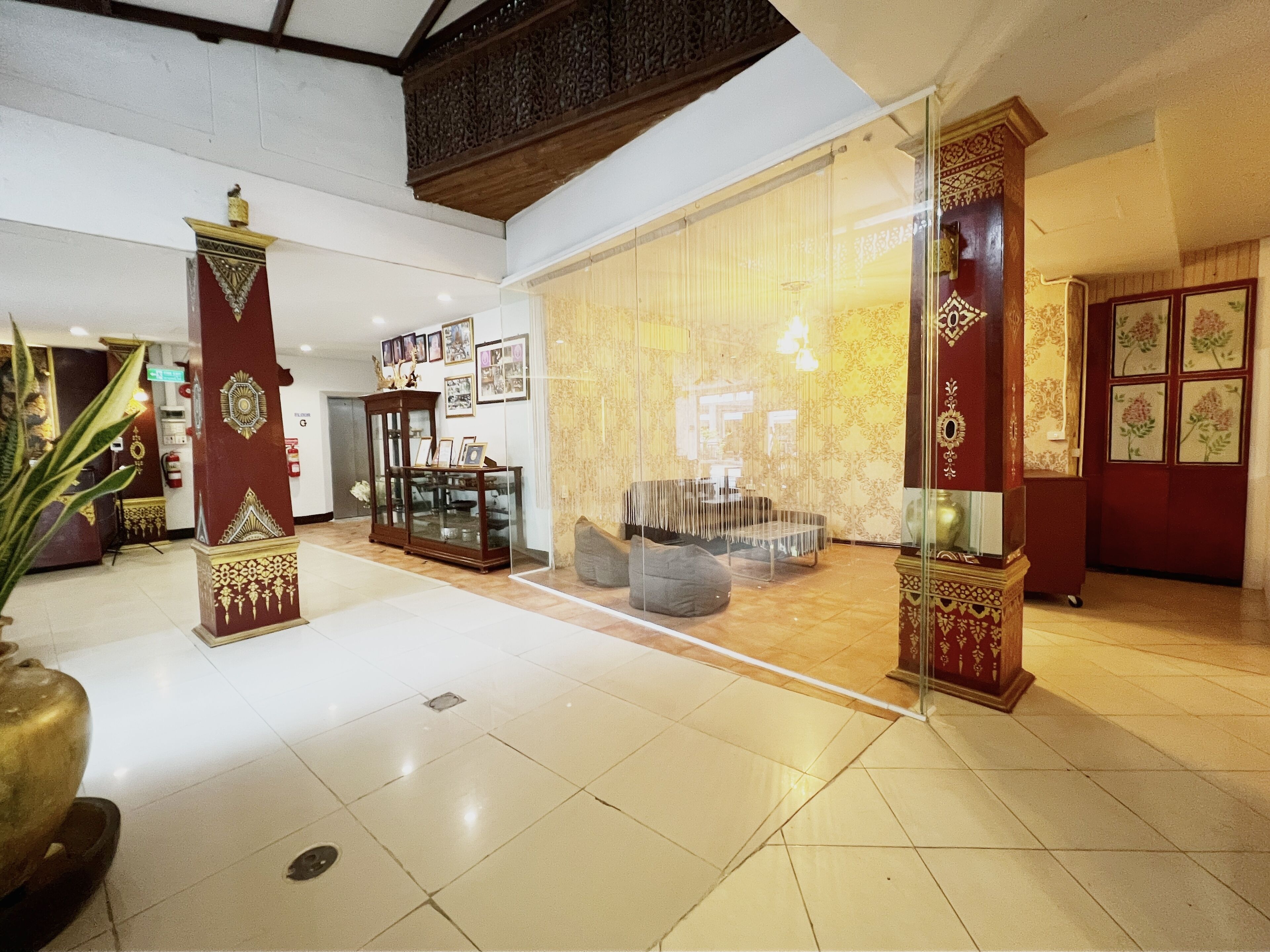 Een ruime lobby met een hoge plafond, een glazen wand en een traditionele houten kolom met ingewikkelde versieringen.