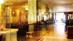 A spacious hotel lobby with a long reception desk, multiple seating areas, and a clear view of the dining area in the background. - Silver Resortel (Patong)