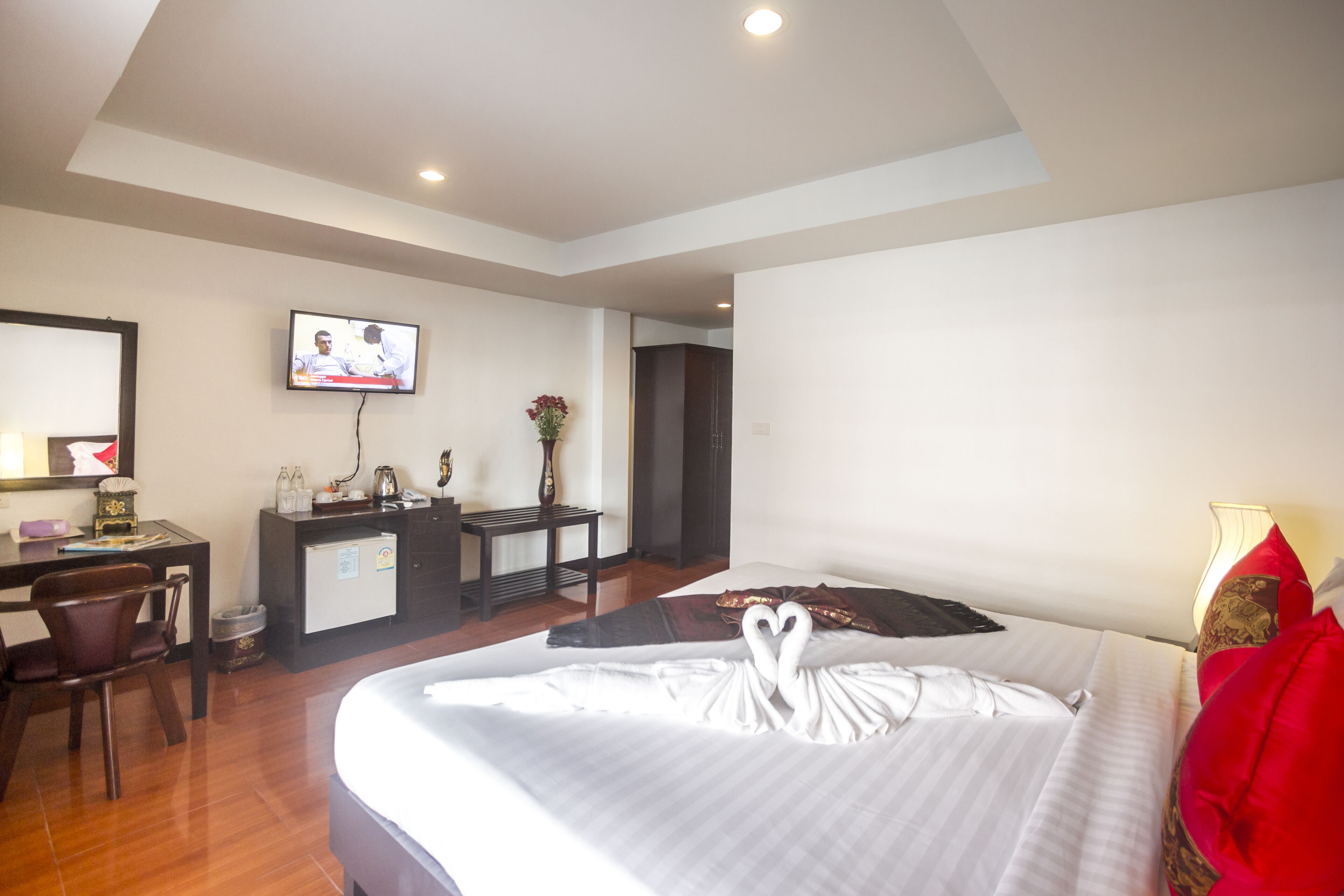 A hotel room with a bed, a desk, a television, and a small refrigerator.