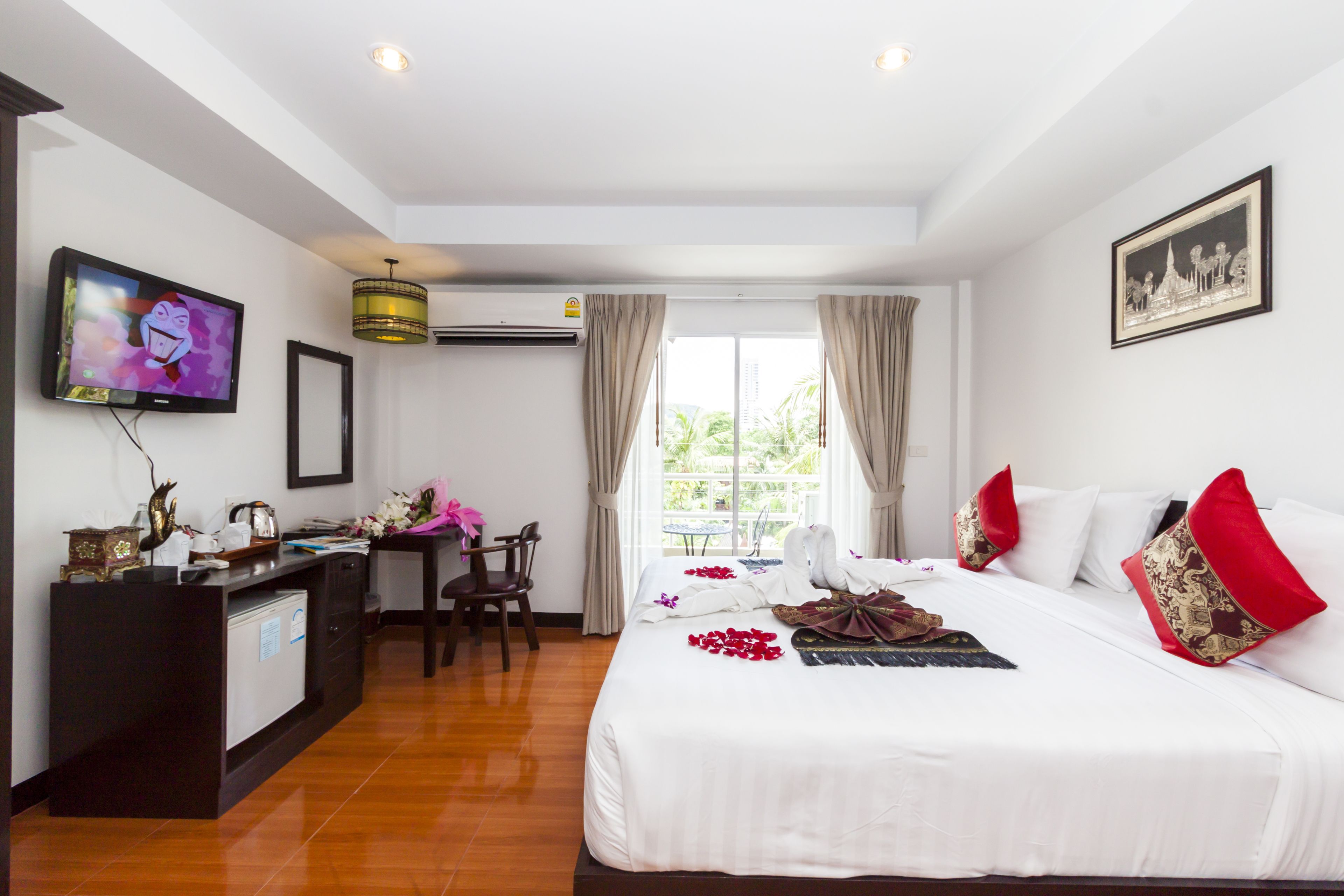 A hotel room with a bed, a desk, a television, and a window with curtains.