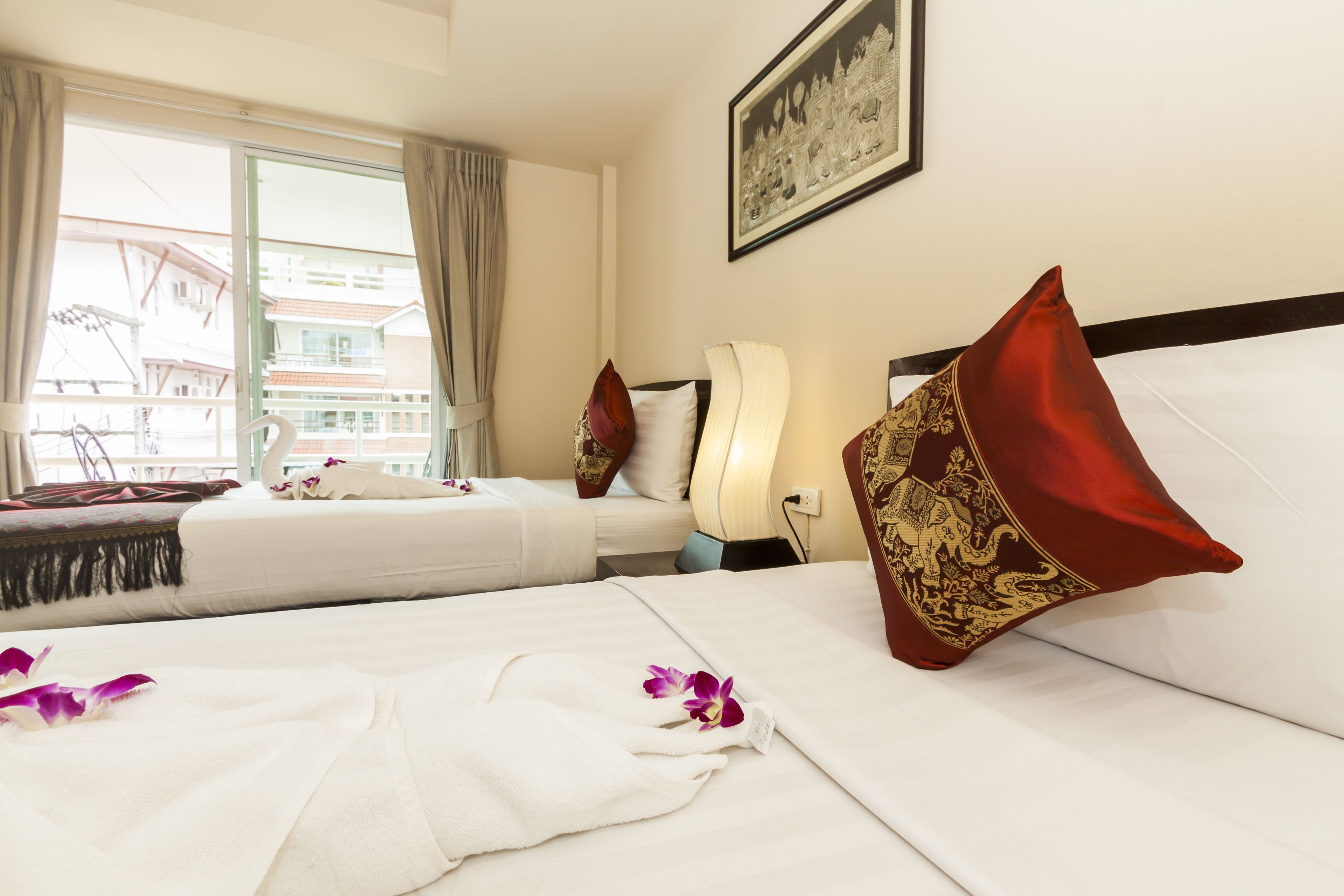 A hotel room with two beds, a large window, and a framed picture on the wall.