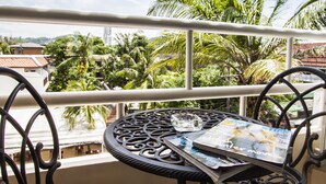 A balcony with a table and chairs, overlooking a residential area with palm trees and houses. - Silver Resortel (Patong)