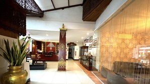 A reception area with a reception desk, a large decorative pillar, and a seating area with a sofa and a chair. - Silver Resortel (Patong)