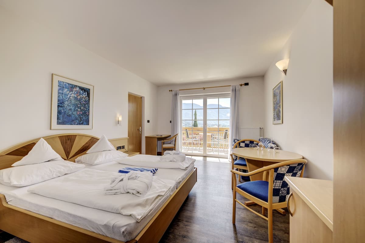 Quarto de hotel com cama, escrivaninha, cadeira e varanda com vista.