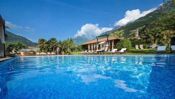 A clear blue pool with lounge chairs and a mountain backdrop.