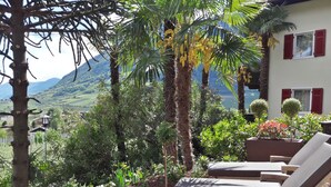 A patio with lounge chairs, a stone pathway, and a view of a mountainous landscape.