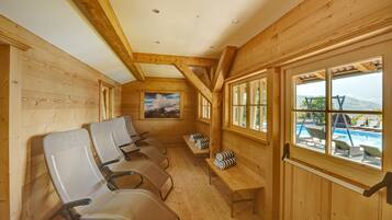 Relax in a cabin-style room with a high ceiling and exposed beams, featuring a seating area and a large window overlooking a swimming pool.