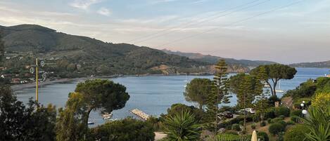 A coastal landscape with a view of the sea, hills, and a pathway leading to a building.