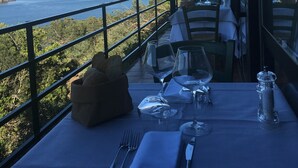 Una mesa preparada para comer con vistas al mar y las colinas.