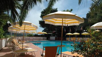 Una piscina al aire libre de temporada, sombrillas