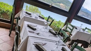 Un restaurante con mesas dispuestas para comer, con vistas panorámicas a colinas y una masa de agua.