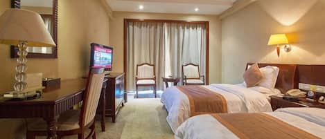 A hotel room with two beds, a desk with a chair, a television, and a lamp.