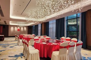 A banquet hall with round tables, white chairs, and red tablecloths. - Xinzhou Haiwan Hotel (Shaoxing)