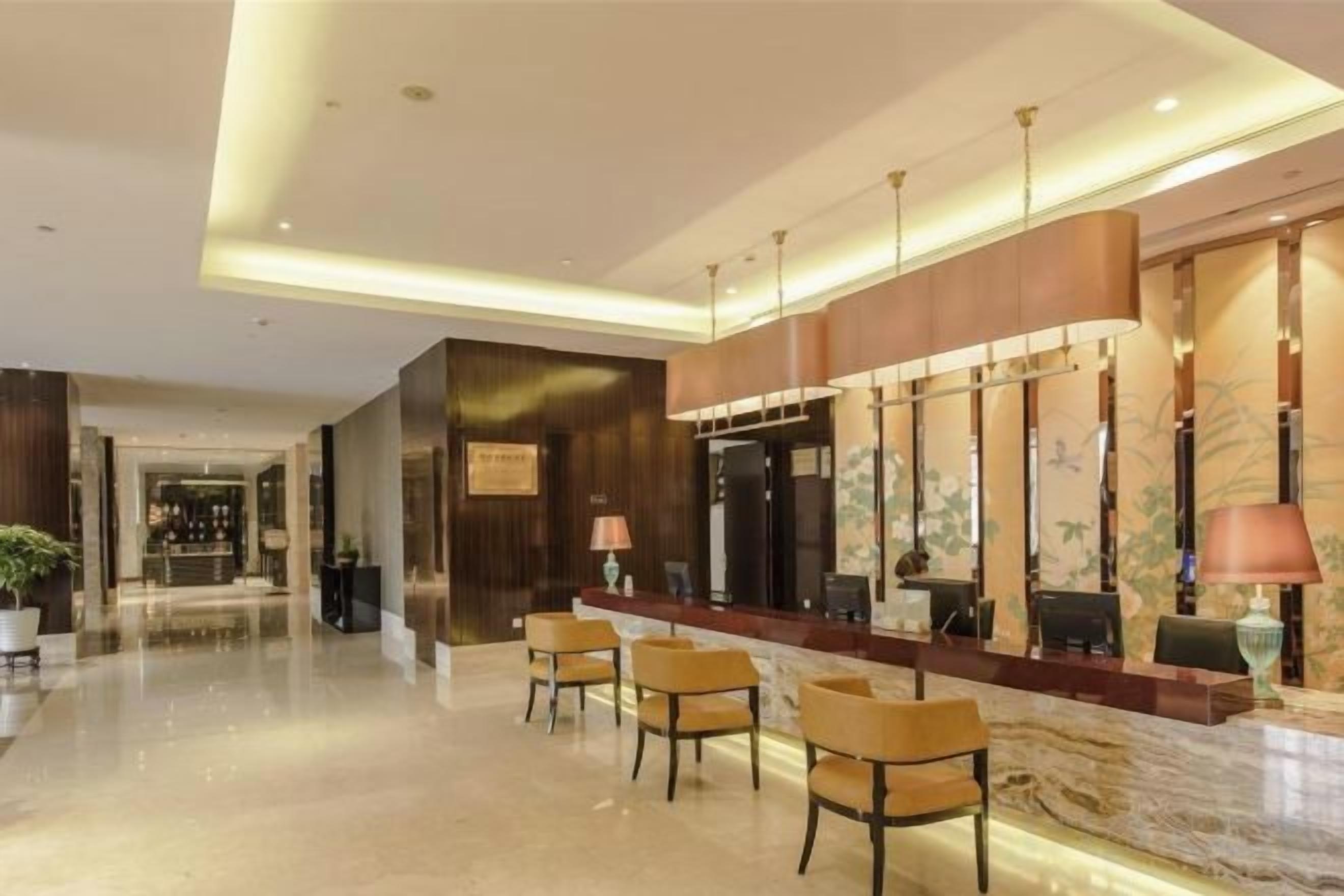 A hotel lobby with a reception desk, seating area, and a large mirror.