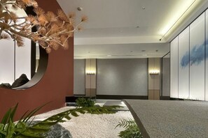 A modern hotel lobby with a reception desk, a large mirror, and a minimalist design. - Xinzhou Haiwan Hotel (Shaoxing)