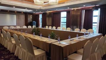 A conference room with a long table, chairs, and a projector screen.