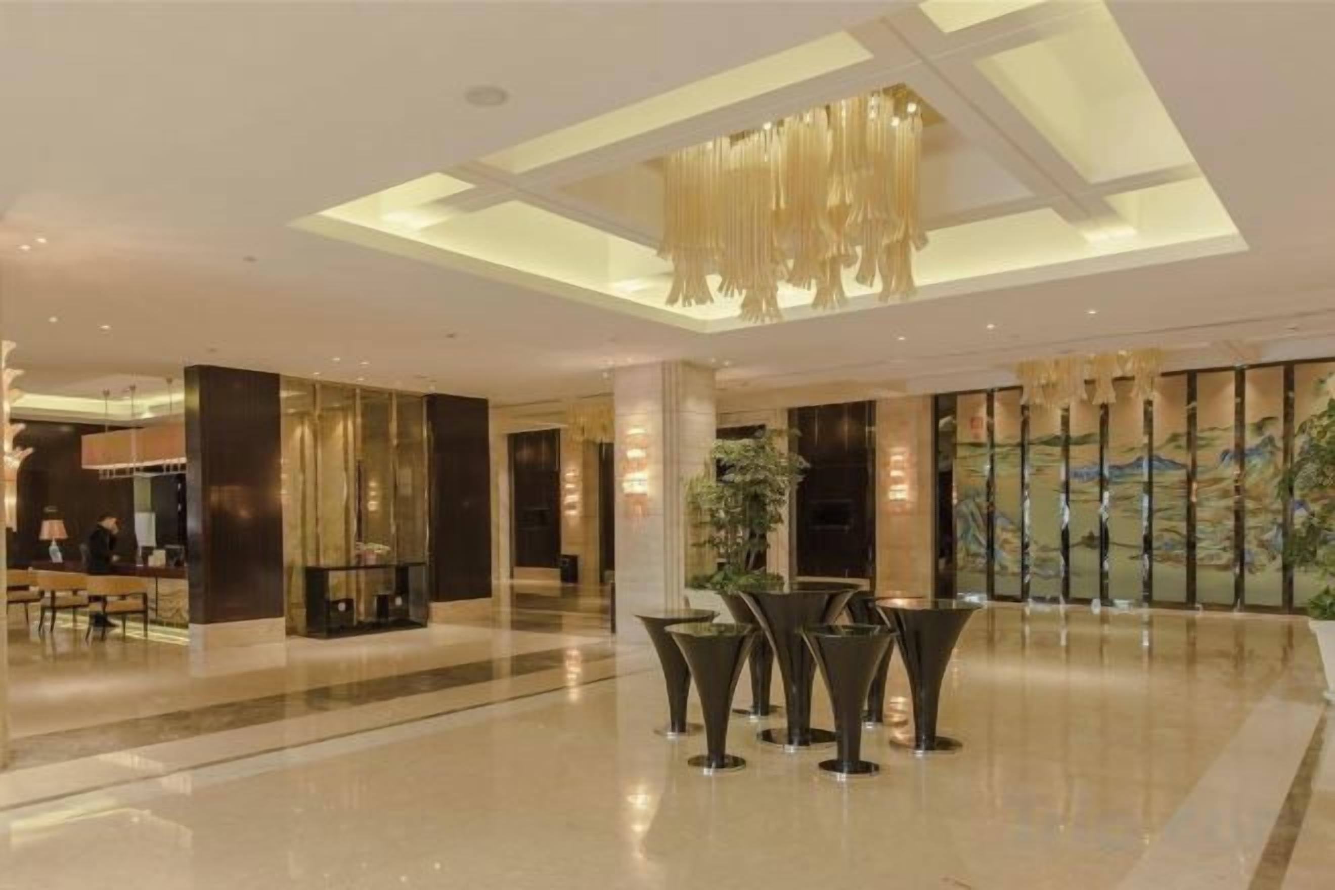 A spacious lobby with a high ceiling, a seating area, and a large window with a view.