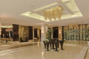 Un'ampia hall con soffitto alto, zona salotto e una grande finestra con vista.