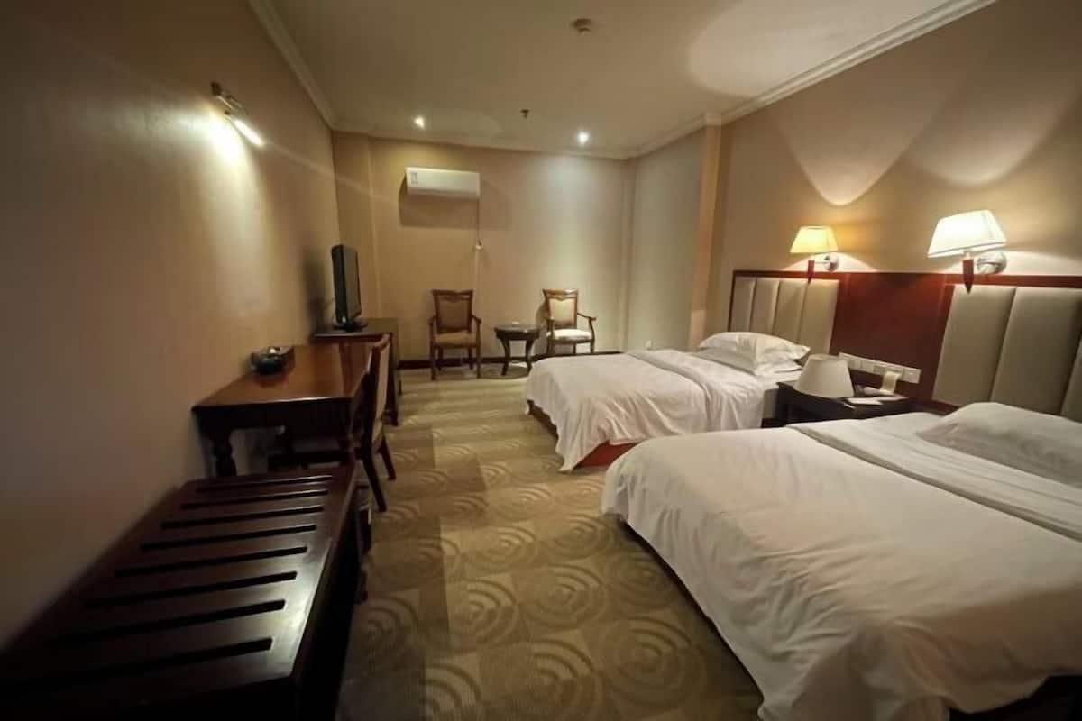 Een hotelkamer met twee bedden, een bureau, een stoel en een televisie.