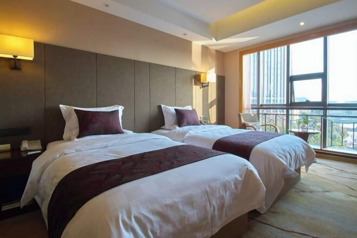 Een hotelkamer met twee bedden, een groot raam met uitzicht en een balkon.