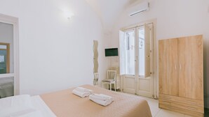 Ett hotellrum med en säng, en garderob, en tv och ett fönster.